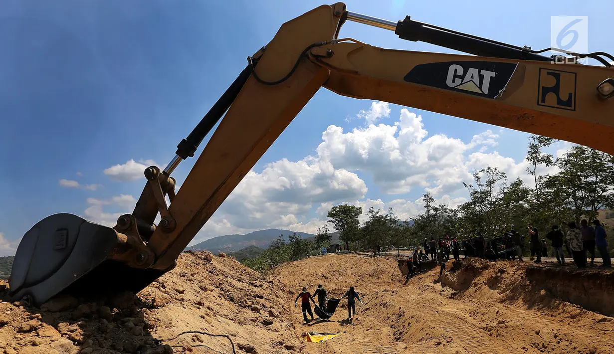 Petugas gabungan membawa kantong jenazah saat pemakaman massal di TPU Peboya Indah, Palu, Sulawesi Tengah, Rabu (3/10). Pemakaman massal tersebut memasuki hari ketiga setelah sebelumnya dilakukan di hari Senin. (Liputan6.com/Fery Pradolo)