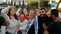 Para pengunjuk rasa anti-pemerintah bergembira setelah PM Lebanon Saad Hariri mengumumkan pengunduran diri, di depan istana pemerintahan di Beirut, Selasa (29/10/2019). Pengunduran diri Saad Hariri disambut sorak-sorai kerumunan pengunjuk rasa yang termobilisasi sejak 17 Oktober. (AP/Bilal Hussein)