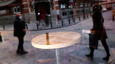 Refleksi orang-orang terlihat dari jendela depan sebuah bar yang tutup di pusat kota Brussel, Belgia, Kamis (8/10/2020). Brussels pada Rabu, 7 Oktober 2020, memutuskan menutup semua bar, ruang dansa, dan kafetaria selama sebulan sebagai upaya membendung lonjakan COVID-19. (AP Photo/Francisco Seco)