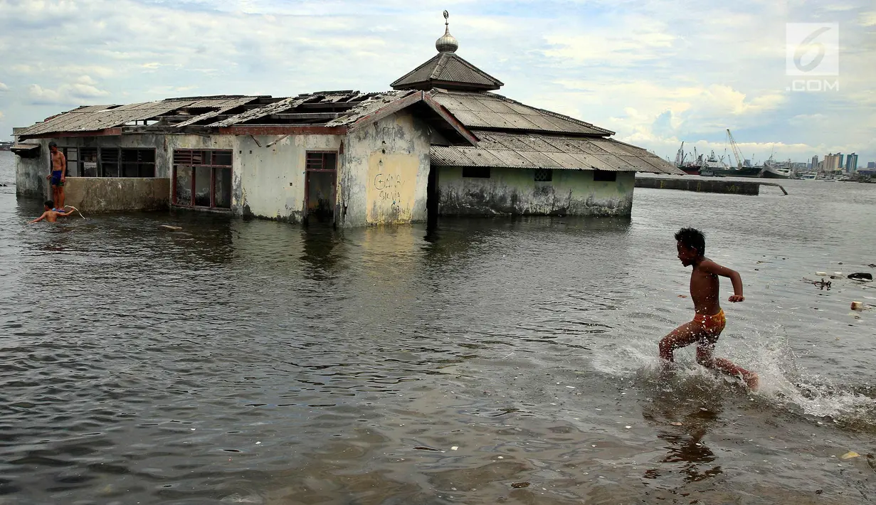 Seorang anak bermain air di Masjid yang terkena Abrasi di kawasan Muara Baru, Jakarta, Kamis (4/1). Anak-anak yang bermukim di kawasan tersebut banyak menghabiskan waktu saat berlibur sekolah untuk bermain di laut. (Liputan6.com/Johan Tallo)