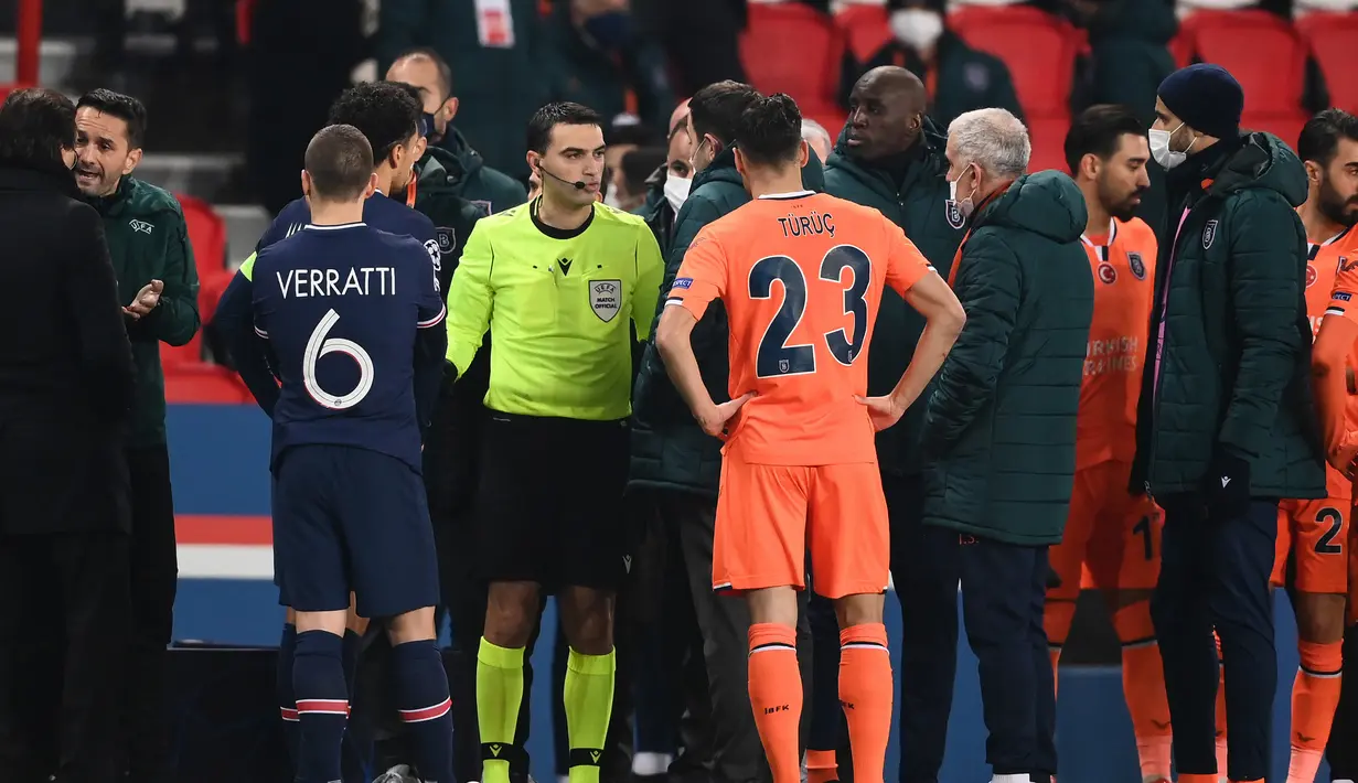 Wasit Ovidiu Hategan berbicara dengan ofisial tim istanbul Basaksehir usai dihentikannya laga lanjutan Liga Champions Grup H melawan Paris Saint-Germain di Parc des Princes Stadium, Selasa (8/12/2020). (AFP/Franck Fife)
