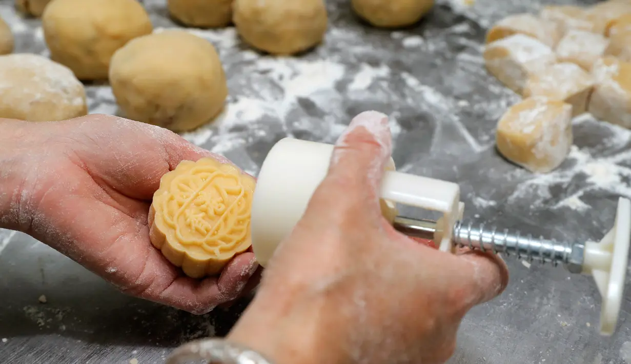 Pekerja mencap kata-kata China 'Orang Hong Kong' pada kue bulan di toko roti Wah Yee Tang, Hong Kong, 9 Agustus 2019. Selain 'Orang Hong Kong', toko roti ini juga mencap kue bulan buatannya dengan kata-kata 'Mari Berjuang Bersama' dan 'Jadilah Air'. (AP Photo/Kin Cheung)