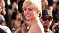 Miley Cyrus mempersilakan seorang pemuda dengan rambut pirang gondrong ke panggung untuk menerima hadiah dan berpidato menggantikannya.