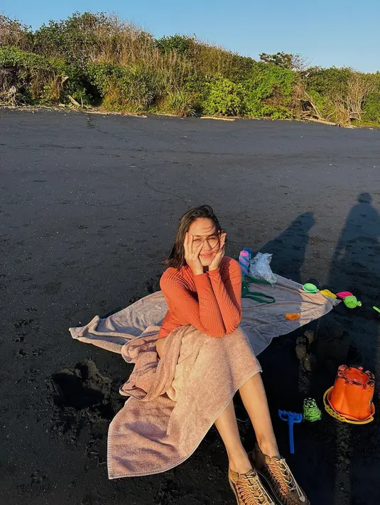 Atau potret manis Pevita saat menikmati waktu santai di pinggir pantai. Ia duduk di atas kain mengenakan outfit berwarna oranye. [Foto: Instagram/pevpearce]
