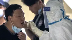 Seorang pekerja mengenakan baju pelindung mengambil swab untuk tes COVID-19 di fasilitas pengujian virus corona di Beijing, China, Sabtu (23/4/2022). Beijing dalam keadaan waspada setelah 10 siswa sekolah menengah dinyatakan positif COVID-19 pada hari Jumat, yang menurut pejabat kota sebagai putaran awal pengujian. (AP Photo/Mark Schiefelbein)