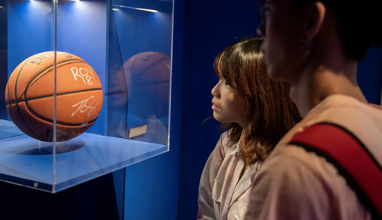 Pengunjung melihat bola basket bertanda tangan pendatang baru terbaik Ben Simmons dalam pameran NBA (National Basketball Association) di Beijing, China, Senin (19/8/2019). (NICOLAS ASFOURI/AFP)