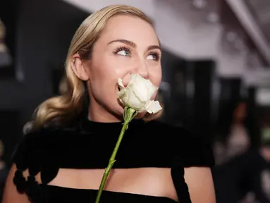 Miley Cyrus membawa mawar putih ketika menghadiri karpet merah Grammy Awards 2018 di New York, Minggu (28/1). Bunga ini menjadi lambang untuk dukungan melawan kesetaraan gender dan pelecehan seksual di industri musik. (Christopher Polk/Getty Images/AFP)