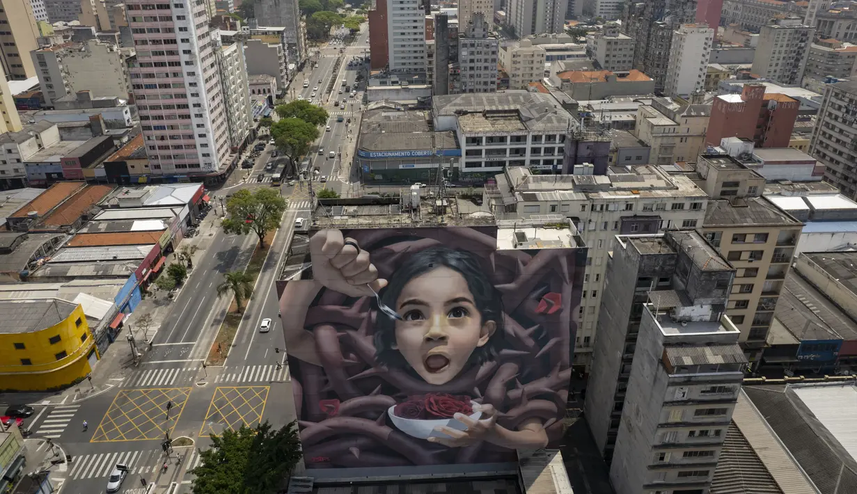 Sebuah mural raksasa karya seniman yang dikenal sebagai BIP, dipajang di dinding bangunan di Sao Paulo, Brasil, Rabu (29/9/2021). Para seniman mural papan atas dikerahkan membuat lukisan raksasa karya terbaik mereka untuk berpartisipasi dalam festival selama seminggu. (AP Photo/Andre Penner)