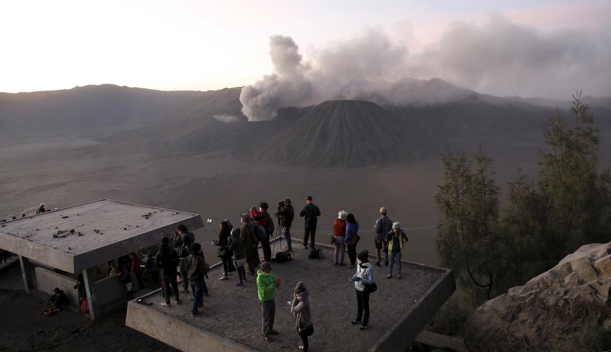 Wisatawan menyaksikan matahari terbit dengan latar belakang Gunung Bromo yang sedang erupsi di Ngadisari, Probolinggo, Jawa Timur, Rabu (6/1/2016). (REUTERS/Darren Whiteside)