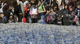 Anak-anak mengambil gambar patung paus raksasa, Plasticus yang dipajang di depan Auditorium Parco della Musica, Roma, Italia, Senin (16/4). Plasticus dibuat untuk meningkatkan kesadaran tentang masalah pencemaran plastik di laut. (Andreas SOLARO/AFP)