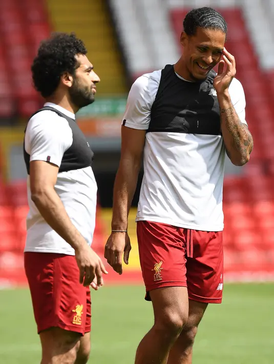 Gelandang Liverpool, Mohamed Salah berbincang dengan Virgil van Dijk saat latihan tim di stadion Anfield, Inggris (21/5). Salah menjalani musim perdana yang apik bersama Liverpool dengan sederet rekor spesial yang telah ditorehkan. (AP Photo/Paul Ellis)