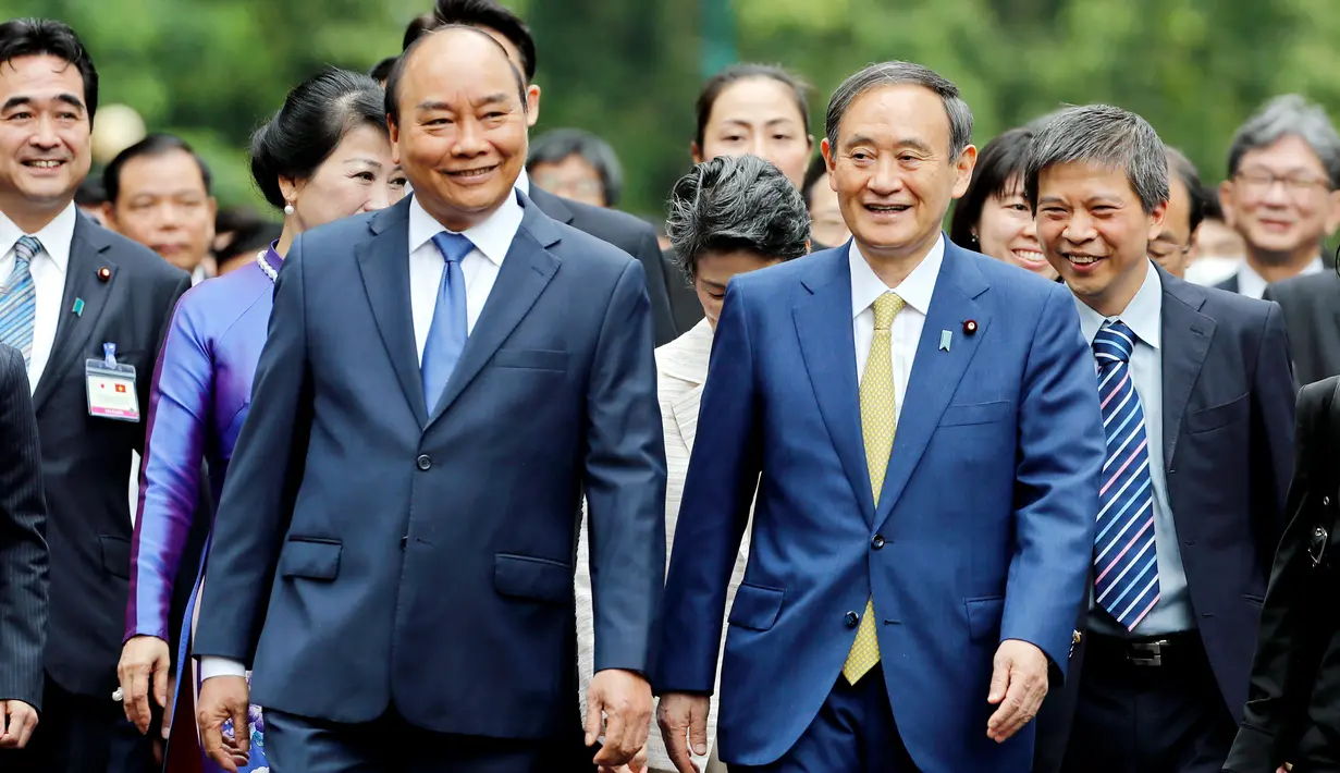 PM Jepang, Yoshihide Suga (kanan tengah) berjalan bersama dengan PM Vietnam, Nguyen Xuan Phuc (kiri depan) setibanya di Istana Kepresidenan, di Hanoi, Vietnam, Senin (19/10/2020). Yoshihide Suga melakukan kunjungan resmi ke Vietnam hingga 20 Oktober 2020.  (AP Photo/Minh Hoang, Pool)