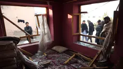 Penduduk desa berdiri di dekat sebuah rumah yang hancur setelah serangan di Kabul, Afghanistan (15/1). Empat orang tewas dan 113 orang lainnya terluka akibat ledakan yang terjadi di dekat kompleks asing tersebut. (AP Photo/Rahmat Gul)