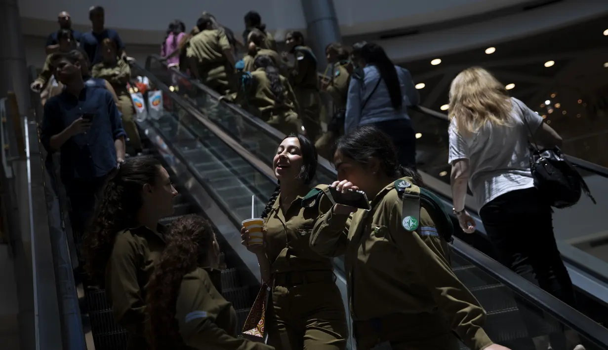 Orang-orang menaiki eskalator di pusat perbelanjaan setelah aturan yang mewajibkan pemakaian masker di dalam ruangan dicabut, di Tel Aviv, Selasa (15/6/2021). Israel mencabut salah satu aturan virus corona terakhirnya pada Selasa setelah program vaksinasi dianggap sukses. (AP Photo/Oded Balilty)
