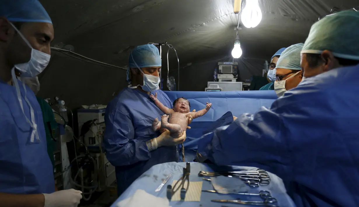 Dokter asal Maroko, menggendong bayi Siwar yang lahir melalui cesar di rumah sakit kamp pengungsian Al Zaatari, Yordania, 7 Maret 2016. Siwar adalah anak ketiga dari keluarga Daraa asal Suriah yang lahir di kamp pengungsian. (REUTERS/Muhammad Hamed)