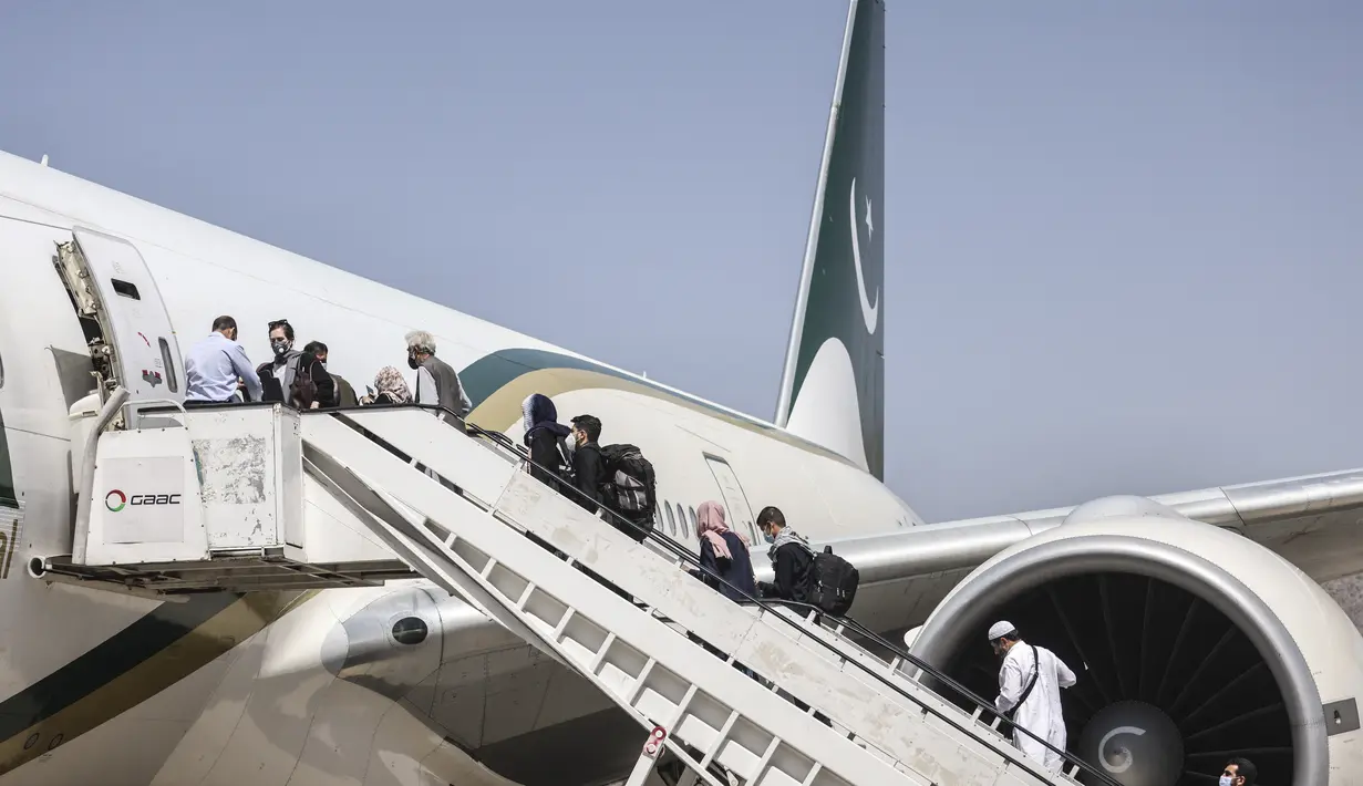 Penumpang menaiki pesawat Pakistan International Airlines (PIA) di bandara di Kabul, Afghanistan, Senin (13/9/2021). Pesawat itu tercatat sebagai penerbangan komersial internasional pertama yang mendarat sejak Taliban merebut kembali kekuasaan di Afghanistan pada Agustus lalu. (Karim SAHIB/AFP)