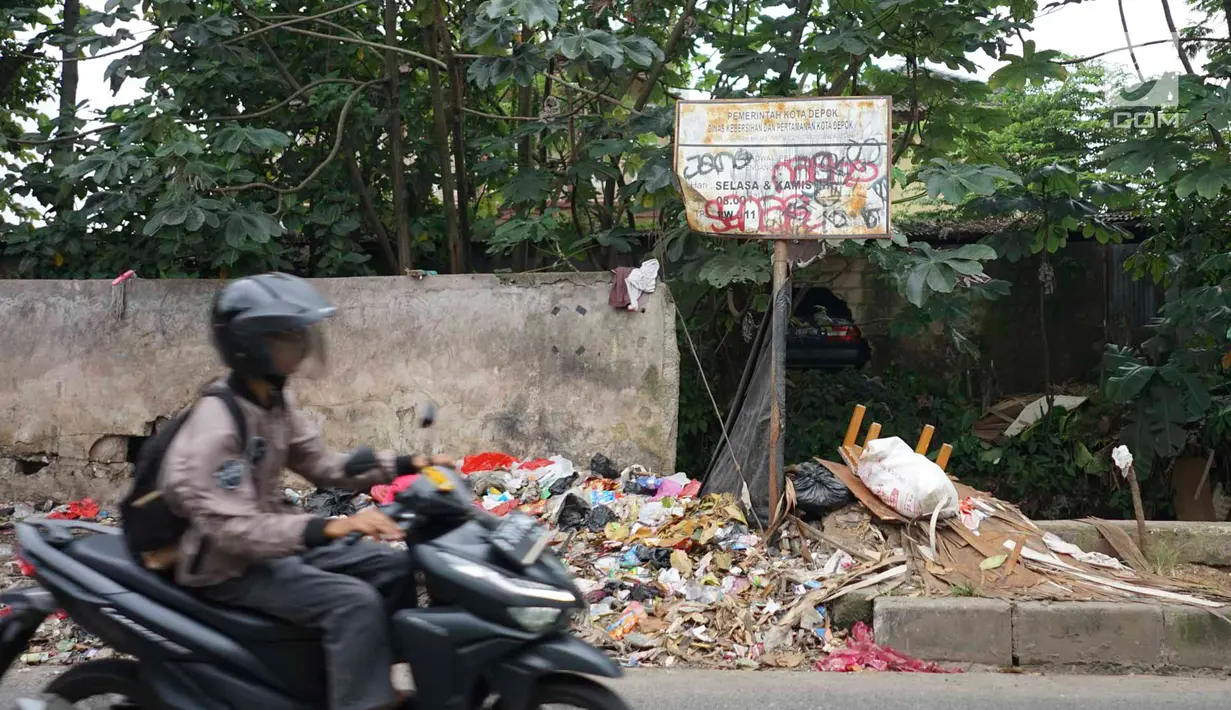 Pengendara melintasi tumpukan sampah rumah tangga di Jalan Raya Tanah Baru kawasan Depok, Jawa Barat, Rabu (15/5/2019). Kurangnya tempat penampungan membuat warga terpaksa membuang sampah di lokasi tersebut, meskipun menimbulkan bau tidak sedap serta mengotori jalan. (Liputan6.com/Immanuel Antonius)