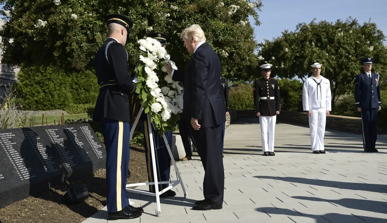 Presiden AS Donald Trump meletakkan karangan bunga usai peringatan serangan 11 September 2001 di Pentagon Memorial, Washington, Senin (11/9). Serangan itu menewaskan sekitar 3.000 orang dan hampir semua dimakamkan di sana. (Brendan Smialowski/AFP)