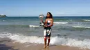 Petenis Jepang, Naomi Osaka menunjukkan trofi juara tunggal putri Australia Terbuka di Pantai Brighton Melbourne, Australia, Minggu (27/1). Prestasi ini membuat Osaka merengkuh gelar Grand Slam secara beruntun. (AP Photo/Kin Cheung)