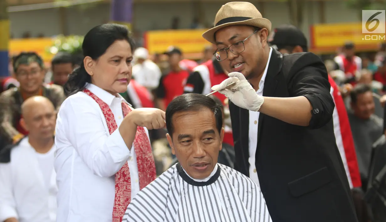 Presiden Joko Widodo disaksikan Ibu Negara Iriana saat mengikuti acara cukur rambut massal di Garut, Jawa Barat, Sabtu (19/1). Jokowi ikut cukur rambut bersama puluhan warga Garut lainnya. (Liputan6.com/Angga Yuniar)