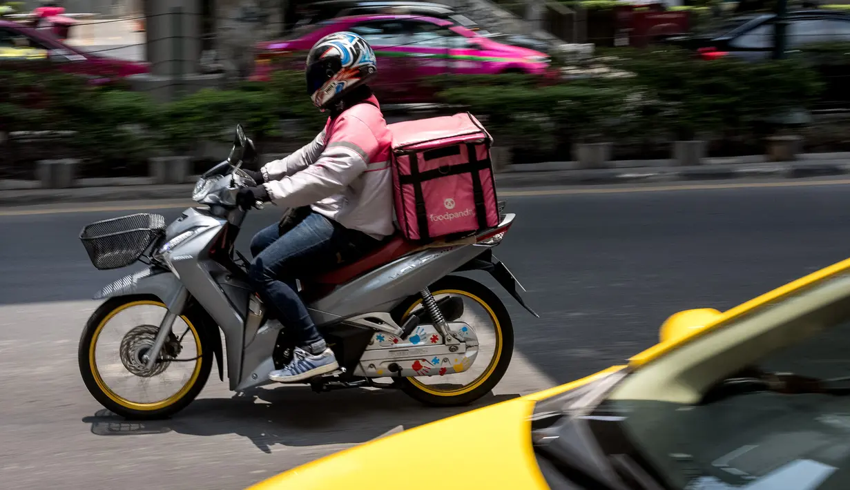 Pengemudi pengantar makanan foodpanda mengendarai sepeda motornya di Bangkok, Selasa (4/5/2021). Operator pengiriman makanan online di Thailand meningkat saat restoran diperintahkan hanya memberikan layanan take away di tengah gelombang virus corona Covid-19 terbaru. (Jack TAYLOR/AFP)