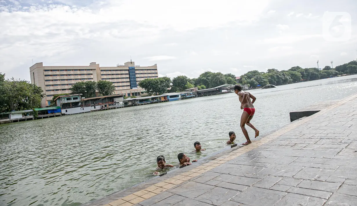 Sejumlah anak berenang di Danau Sunter, Jakarta, Selasa (2/2/2021). Minimnya lahan bermain anak membuat mereka memanfaatkan tempat yang tidak semestinya untuk bermain karena adanya risiko hanyut dan tenggelam bila tidak mampu untuk berenang. (Liputan6.com/Faizal Fanani)