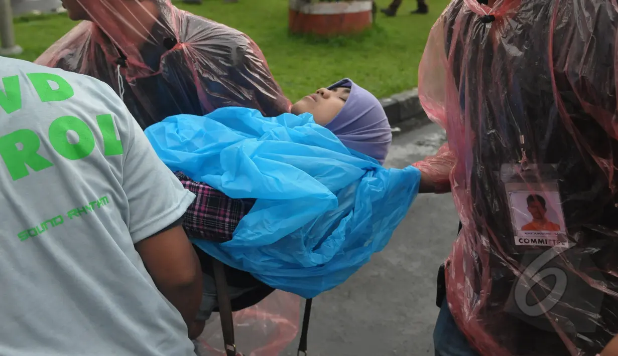 Petugas mengamankan seorang wanita yang pingsan saat mengantre untuk menonton konser One Direction, Senayan, Jakarta, Rabu (25/3/2015). Puluhan ribu orang rela mengantre untuk melihat konser One Direction. (Liputan6.com/Johan Tallo)
