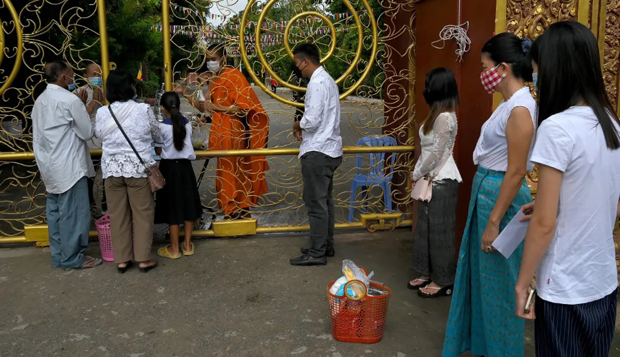 Warga antre untuk memberikan makanan dan sedekah kepada biksu Buddha saat Festival Pchum Ben (Festival Kematian) di luar pagoda di Phnom Penh, Kamboja, 24 September 2021. Pihak berwenang menghentikan perayaan Festival Kematian karena pandemi COVID-19. (TANG CHHIN Sothy/AFP)