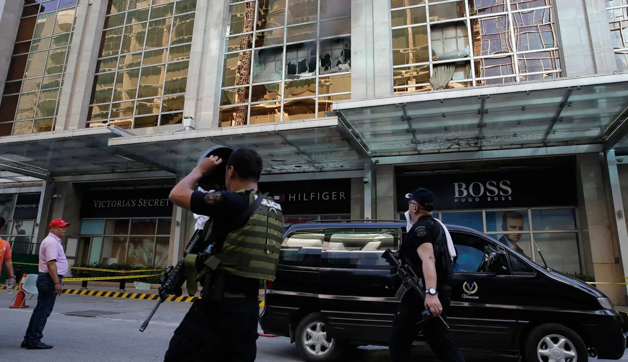 Anggota kepolisian melintasi area hotel yang berasap di kompleks Resorts World Manila, Filipina, Jumat (2/6). Seorang pria bersenjata melakukan serangan dengan menembaki ke arah pengunjung dan meja kasino yang ada di dalam hotel. (AP Photo/Aaron Favila)