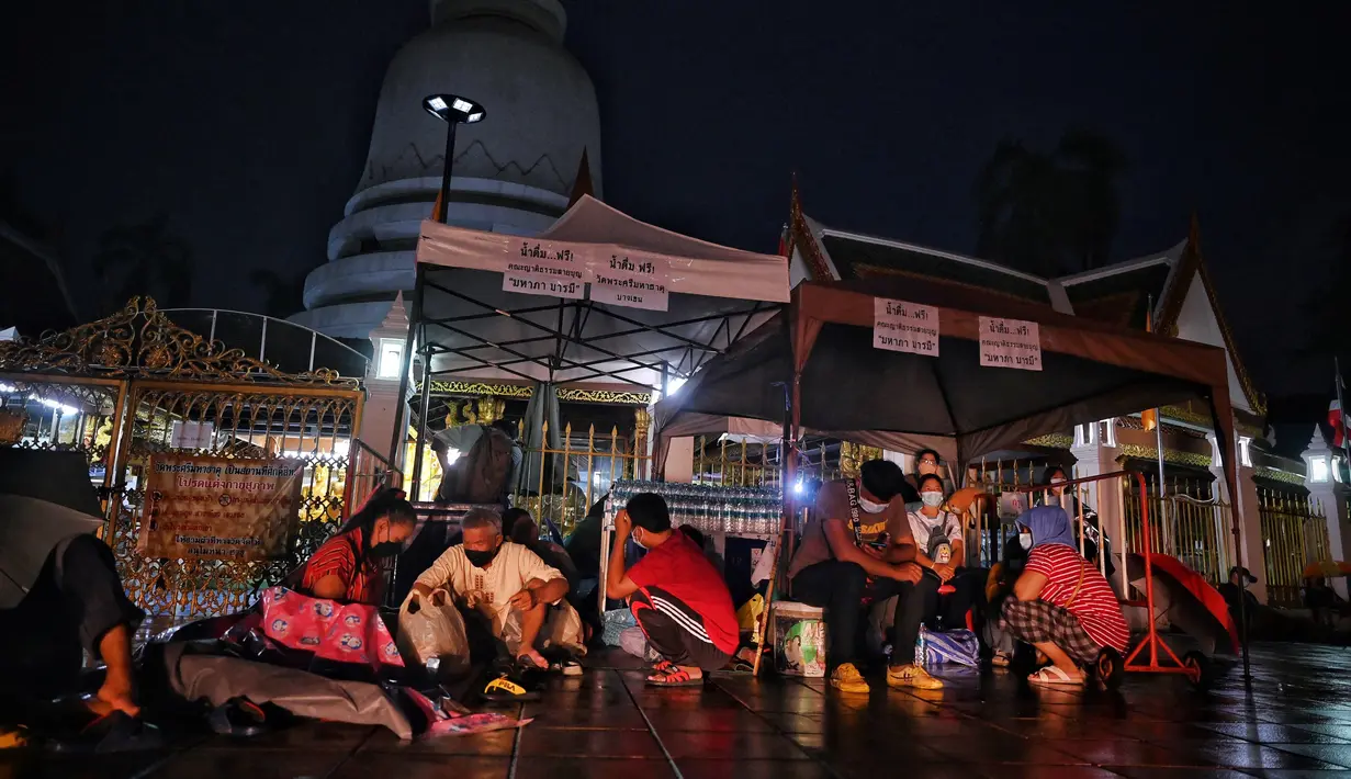 Orang-orang berkerumun di bawah tenda saat mereka antre semalaman untuk tes swab Covid-19 gratis di Wat Phra Sri Mahathat Woramahawihan di Bangkok, Jumat (9/7/2021) dinihari. Thailand pada Kamis (8/7/2021), mencatat rekor 75 kematian Covid-19 dalam 24 jam terakhir. (Lillian SUWANRUMPHA/AFP)