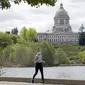 Seseorang memakai masker saat jogging di dekat Capitol di Olympia, Washington, Selasa (27/4/2021). Warga Amerika Serikat (AS) yang telah menerima vaksin COVID-19 tidak lagi diwajibkan mengenakan masker saat berada di luar ruangan jika tidak ada kerumuman. (AP Photo/Ted S. Warren)