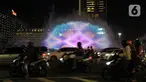 Pengendara melintas dekat water screen yang sedang di uji coba untuk perayaan malam tahun baru di Bundaran HI, Jakarta, Sabtu (30/12/2023). (merdeka.com/Imam Buhori)