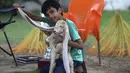 <p>Yasir Ali, anak peternak Mohammad Hasan Narejo memamerkan telinga anak kambing Simba, di Karachi pada 6 Juli 2022. Peternaknya, Mohammad Hassan Narejo, telah mengirimkan detail telinga Simba ke Guinness Book of Records, meskipun dia tidak yakin kambingnya memenuhi kriteria. (Asif HASSAN / AFP)</p>