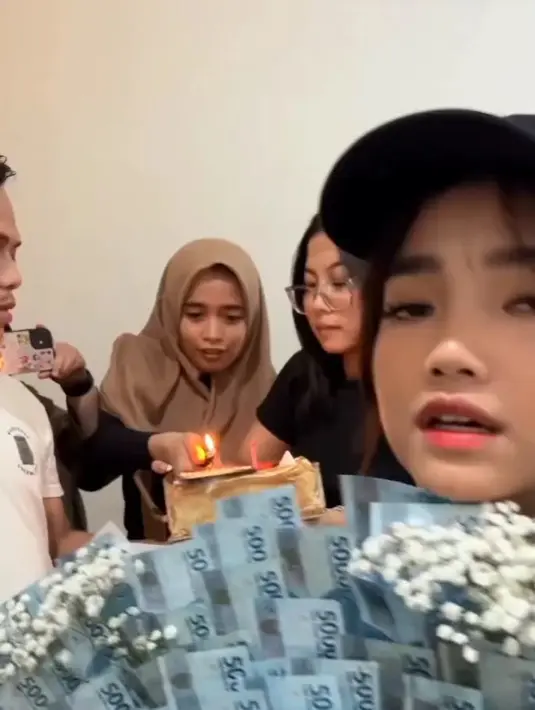 Fuji memegang buket uang dengan pecahan Rp 50 ribuan. Buket tersebut tampak besar dan mencapai jutaan rupiah. Tampak beberapa karyawannya menyalakan lilin. [Instagram/fujiasnaawi]