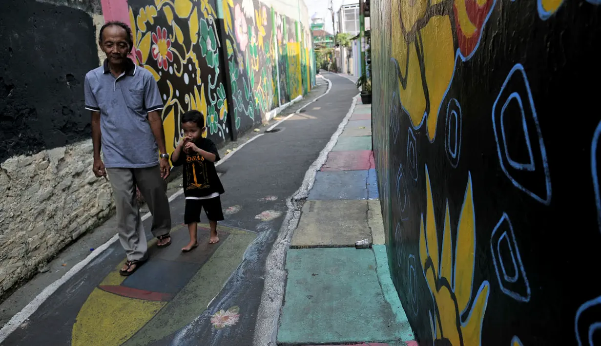 Warga melintas di antara tembok warna-warni di Kampung Pelangi, Johar Baru, Jakarta, Rabu (2/5). (Merdeka.com/Iqbal Nugroho)