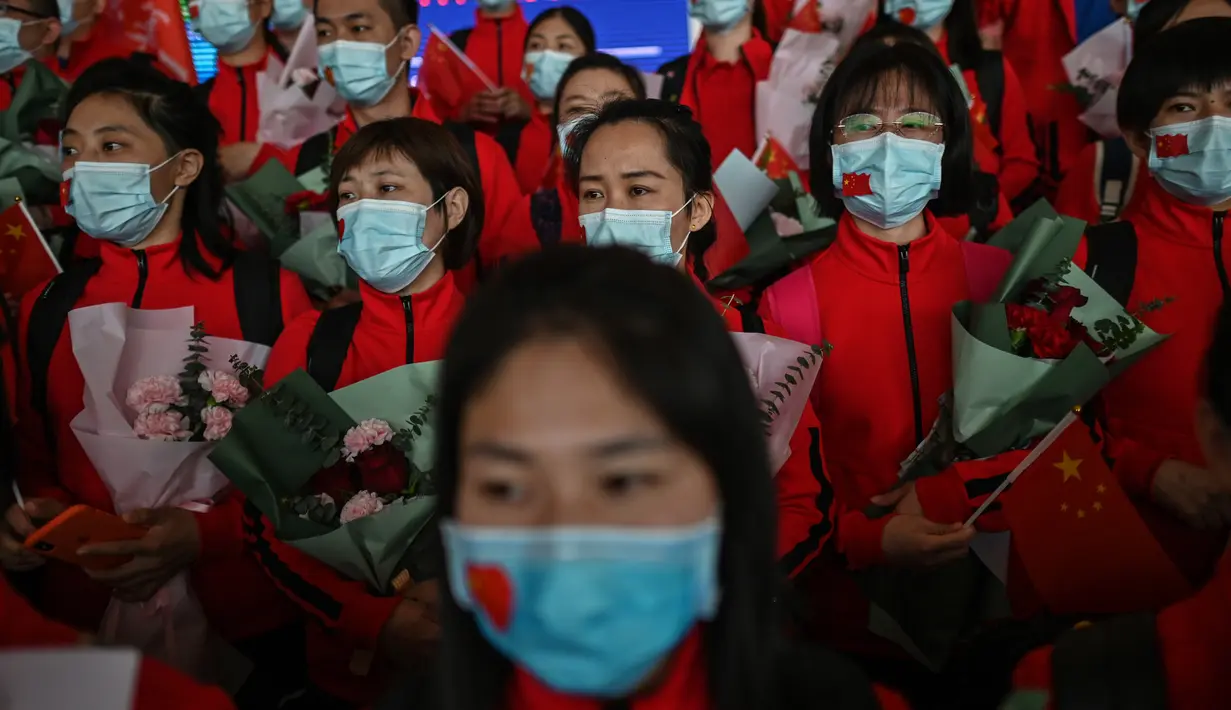 Staf medis dari Provinsi Jilin yang menangani pandemi Covid-19 berpartisipasi dalam upacara pelepasan di Bandara Tianhe, Wuhan, provinsi Hubei, Rabu (8/4/2020). Pemulangan staf medis ini bersamaan dengan pencabutan lockdown di Wuhan yang telah diberlakukan selama 11 minggu. (Hector RETAMAL/AFP)