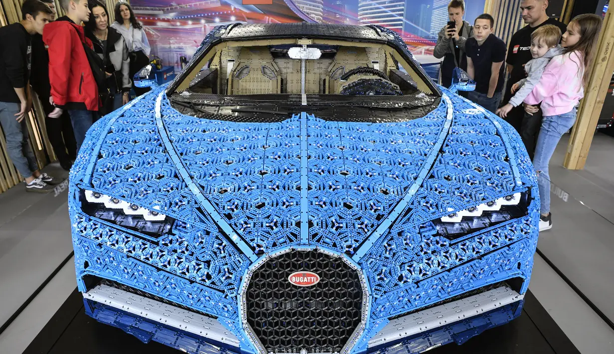 Pengunjung mengamati replika mobil Bugatti Chiron dari jutaan balok Lego Technic pada pameran di Taman Gorky Moskow, Selasa (23/7/2019). Satu juta keping LEGO ditambah bongkahan mesin yang dipasang tanpa tambahan lem, memakan waktu 13.438 jam, untuk dikembangkan dan dirakit. (Alexander NEMENOV/AFP)