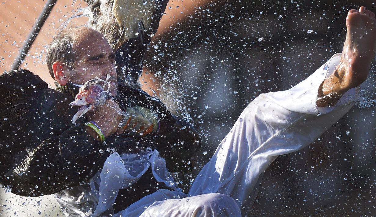 Seorang pemuda bergelayutan pada sebuah tali dengan hanya berpegangan pada kepala seekor angsa mati pada Hari angsa atau Antzar Eguna di Spanyol, Minggu (6/9/2015). Acara ini pernah dikecam oleh para aktivis binatang. (REUTERS/Vincent West)