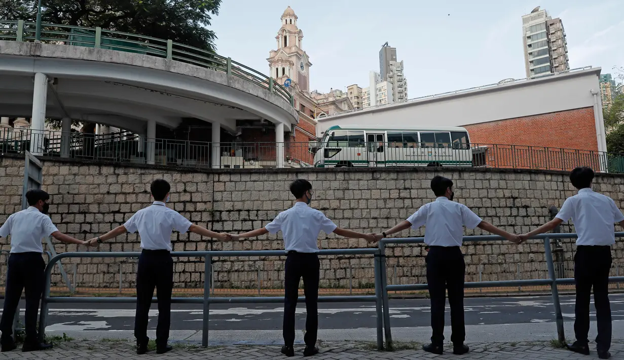 Para siswa saling memegang tangan mengelilingi St. Paul's College di Hong Kong, Senin (9/9/2019). Aksi dilakukan para siswa yang masih berseragam sekolah sebagai bentuk dukungan terhadap demonstran anti pemerintah setelah bentrokan yang terjadi pada akhir pekan lalu. (AP/Kin Cheung)