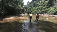 Dua warga Kabupatan Kutai Kartanegara saat hendak memasuki kawasan hutan melalui sungai kecil yang jernih.