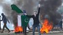 Seorang demonstran mengibarkan bendera Pakistan dan meneriakkan slogan-slogan anti-India saat menggelar aksinya usai melakukan salat Idul Fitri di Srinagar, India (26/6). (AP Photo / Mukhtar Khan)