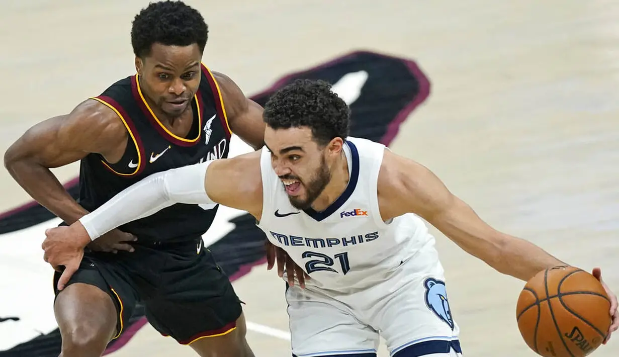 Pebasket Memphis Grizzlies, Tyus Jones, berebut bola dengan pebasket Cleveland Cavaliers, Yogi Ferrell, pada laga NBA, Senin (11/1/2021). Grizzlies menang dengan skor 101-91. (AP/Tony Dejak)