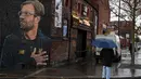 Seorang wanita melintas dekat mural pelatih klub Liverpool, Jurgen Klopp di Jamaica Street, pusat kota Baltic Triangle di Liverpool, Senin (10/12). Pengerjaan mural itu dimulai sejak 8 November 2018 lalu oleh seniman jalanan "Akse". (Paul ELLIS / AFP)
