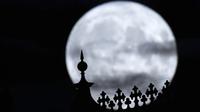 Bulan purnama terbit di atas kastil Schwerin, di Schwerin, Jerman, Selasa, 1 Agustus 2023. Setelah Sturgeon Moon, bulan purnama berikutnya adalah Blue Moon yang jatuh pada 30 Agustus 2023. (Jens Büttner/dpa via AP)