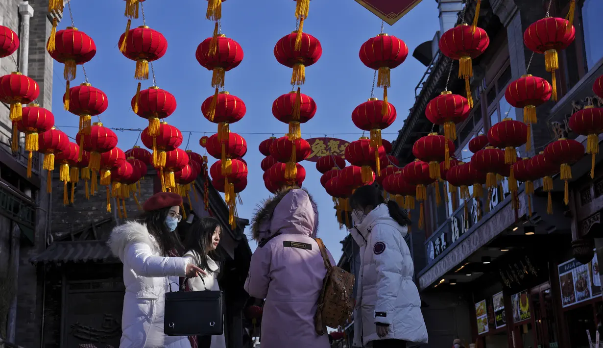 Para perempuan berjalan di bawah lentera merah yang digantung di gang perbelanjaan dekat Danau Houhai untuk merayakan Tahun Baru Imlek di Beijing, Senin, 16 Januari 2023. Organisasi Kesehatan Dunia (WHO) telah mengimbau China untuk terus merilis informasi tentang gelombang infeksi COVID-19 setelah pemerintah mengumumkan hampir 60.000 kematian sejak awal Desember menyusul keluhan selama berminggu-minggu karena gagal memberi tahu dunia apa yang terjadi. (AP Photo/Andy Wong)