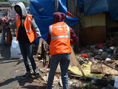 Warga pelanggar PSBB (Pembatasan Sosial Berskala Besar) membersihkan sampah setelah dijatuhi hukuman saat terjaring razia di Pasar Gembrong, Jakarta, Selasa (2/6/2020). Para pelanggar aturan PSBB tersebut dijatuhi sanksi membayar denda atau melakukan pelayanan sosial. (merdeka.com/Imam Buhori)