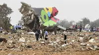 Polisi dan pekerja penyelamat berdiri di antara sisa-sisa Al Afriqiyah Flight 8U771 yang hancur (AP)
