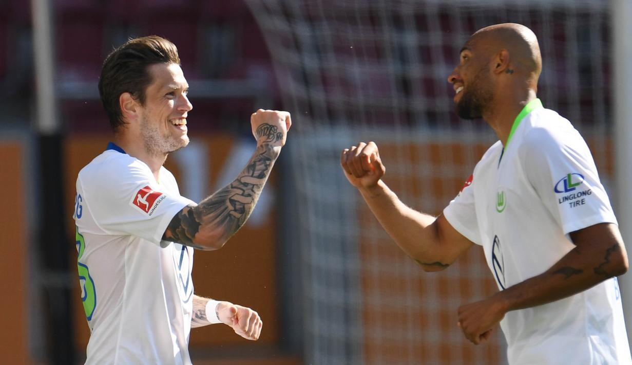 Pemain Wolfsburg Daniel Ginczek dan John Brooks merayakan gol yang dicetak ke gawang FC Augsburg pada laga Bundesliga di Augsburg, Sabtu (16/5/2020). Pandemi COVID-19 membuat pemain melakukan selebrasi jaga jarak. (AFP/Tobias Hase)