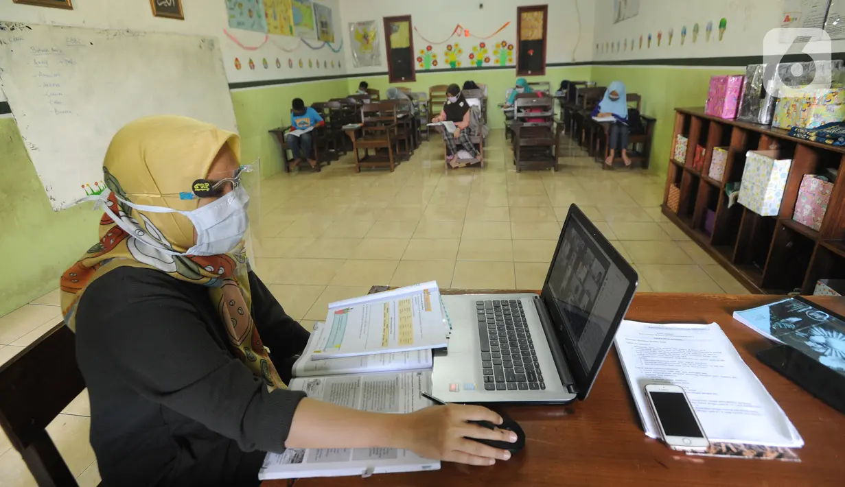 Guru mengajar secara darling sekaligus tatap muka kepada murid-murid SDIT Nurul Amal, Pondok Cabe, Tangerang Selatan, Banten, Senin (16/11/2020).  Proses belajar secara tatap muka atau luring ini merupakan uji coba dengan menggunakan assessment pembatasan jumlah murid. (merdeka.com/Arie Basuki)