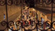 Gambar ini diambil di belakang kisi-kisi balkon pada 29 Agustus 2021 menunjukkan orang-orang berjalan-jalan di "Souq Khan al-Harir" (pasar tertutup sutra) yang dibuka kembali di kota utara Aleppo Suriah setelah upaya rekonstruksi setelah konflik bertahun-tahun. (AFP Photo)